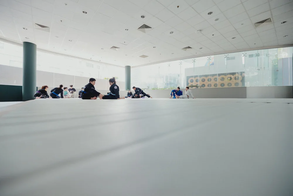 Students stretching on the mats at Kairos Academy, with tall windows behind them
